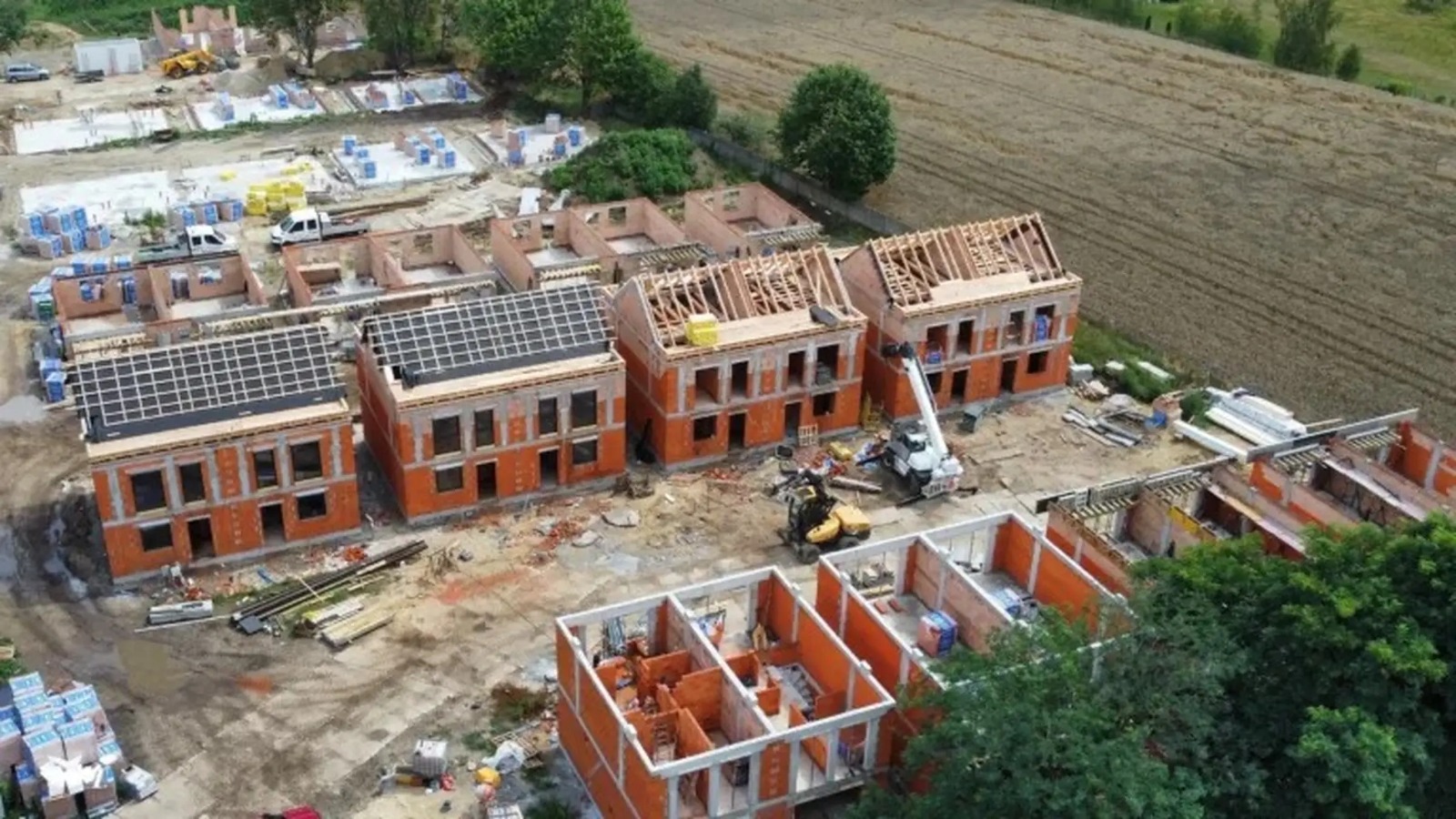 Widok z góry na budowę osiedla — roboty murowe i konstrukcje dachów